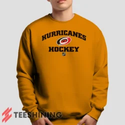 Male model lounging in the Carolina Hurricanes NHL Hockey Men's Sweatshirt in orange. Made from ultra-soft fabric for unmatched comfort.