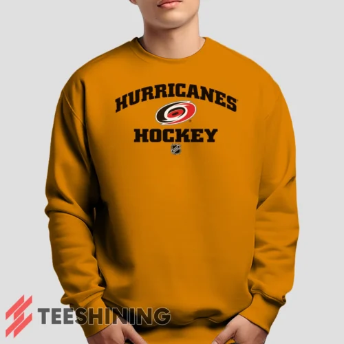 Male model lounging in the Carolina Hurricanes NHL Hockey Men's Sweatshirt in orange. Made from ultra-soft fabric for unmatched comfort.